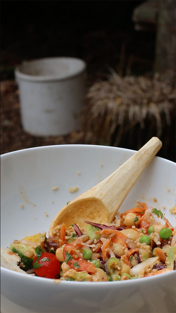 a bowl of bright colourful food with a wooden spoon